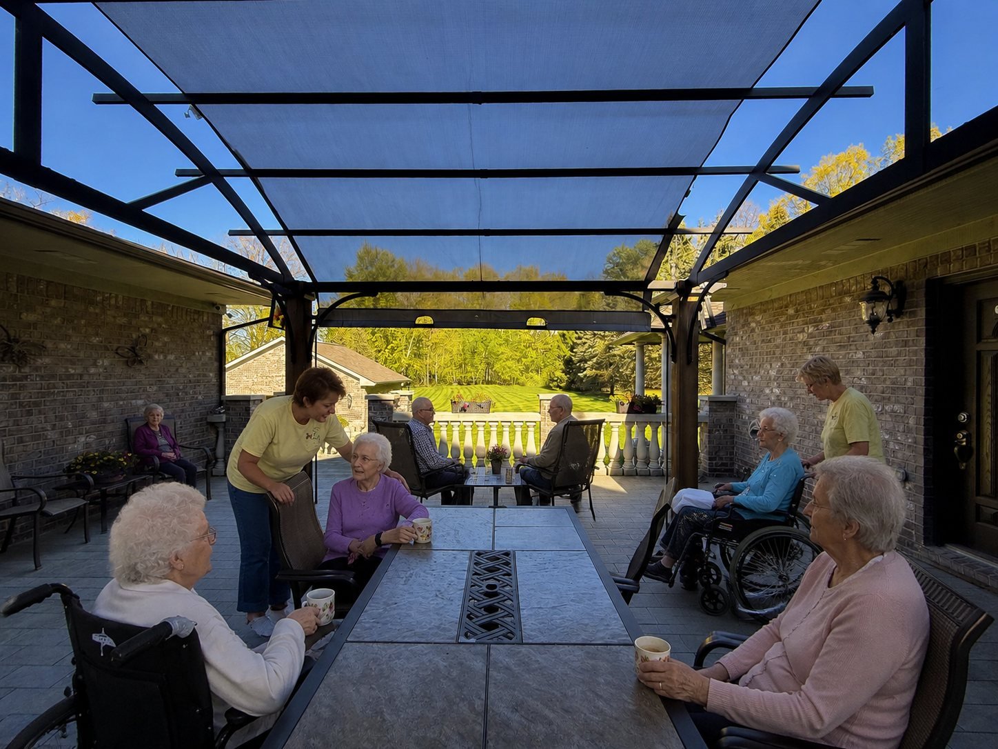 Residents and staff enjoying coffee together on the covered patio